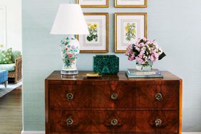 Light blue wall room with antique dresser and botanical prints hung above