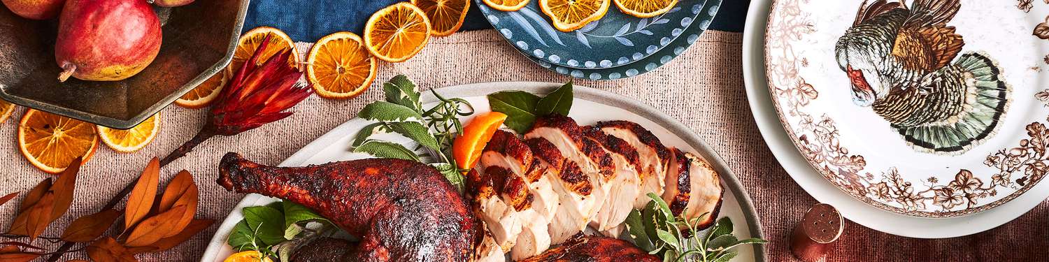 Sliced Thanksgiving turkey set on table with dried leaves and orange slices