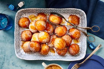 Southern Living Sufganiyot on a platter to serve, dusted with powdered sugar and orange marmalade glaze