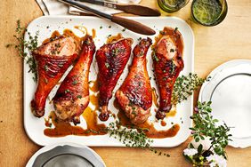 Southern Living Smoked Turkey Legs on a platter to serve, garnished with fresh herbs