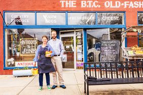 The B.T.C. Old-Fashioned Grocery Store, man and woman standing and smiling outside cheery storefront