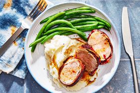 a plate filled with bacon-wrapped tenderloin, mashed potatoes, and green beans