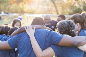 Large group of volunteers huddle up before cleaning up their community.