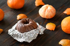 Overhead shot of a chocolate orange inside the wrapper with oranges around it 