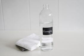 Vinegar in glass bottle with cleaning cloths