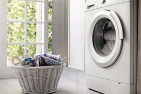 View of laundry room with washing machine and laundry basket with dirty clothes