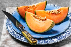 Slices of cantaloupe on a vintage blue plate on gray background