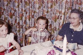 Boy eating cake with sister and grandmother