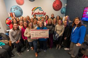 The "Jones 30" pose with Mary Harville, President and CEO of the Kentucky Lottery.