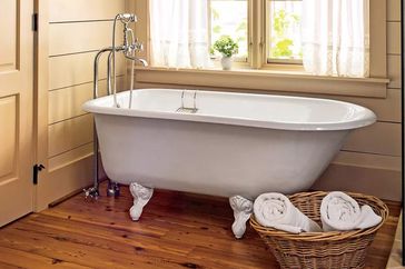 Bathtub by window on wood floor