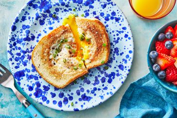 Southern Living Egg in a Hole on a plate with a fork, fruit, and juice beside