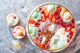 Southern Living Rainbow Sherbet Punch in a punch bowl with a couple of glasses beside