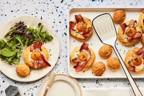 Eggs in biscuits on baking sheet with spatula and a egg in a biscuit on a plate with mixed greens