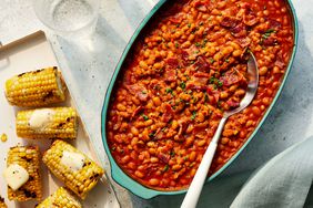 Southern Living Smoky-Sweet Baked Beans in a serving dish with grilled corn beside