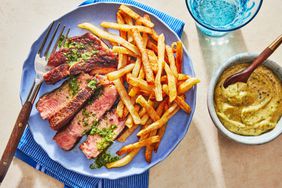 Steak Frites on a blue plate with mustard sauce in a bowl